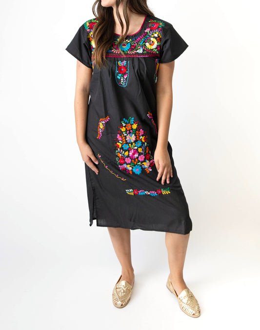 Close-up of bright hand-stitched floral embroidery on women's Mexican dress